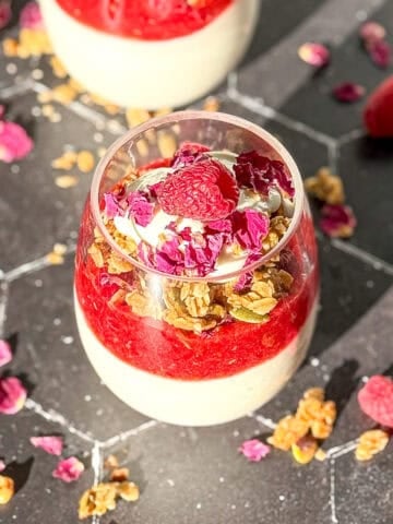 An image of a raspberry rose parfait on a black counter.