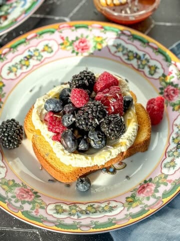 Angle view of lavender honey ricotta toast on a black background.