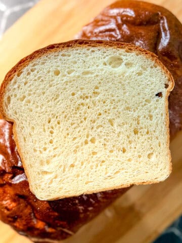 A slice of white bread sitting on top of a loaf of bread.