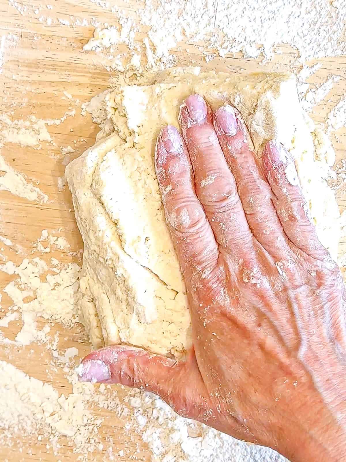 Gently patting biscuit dough into a one inch thickness.