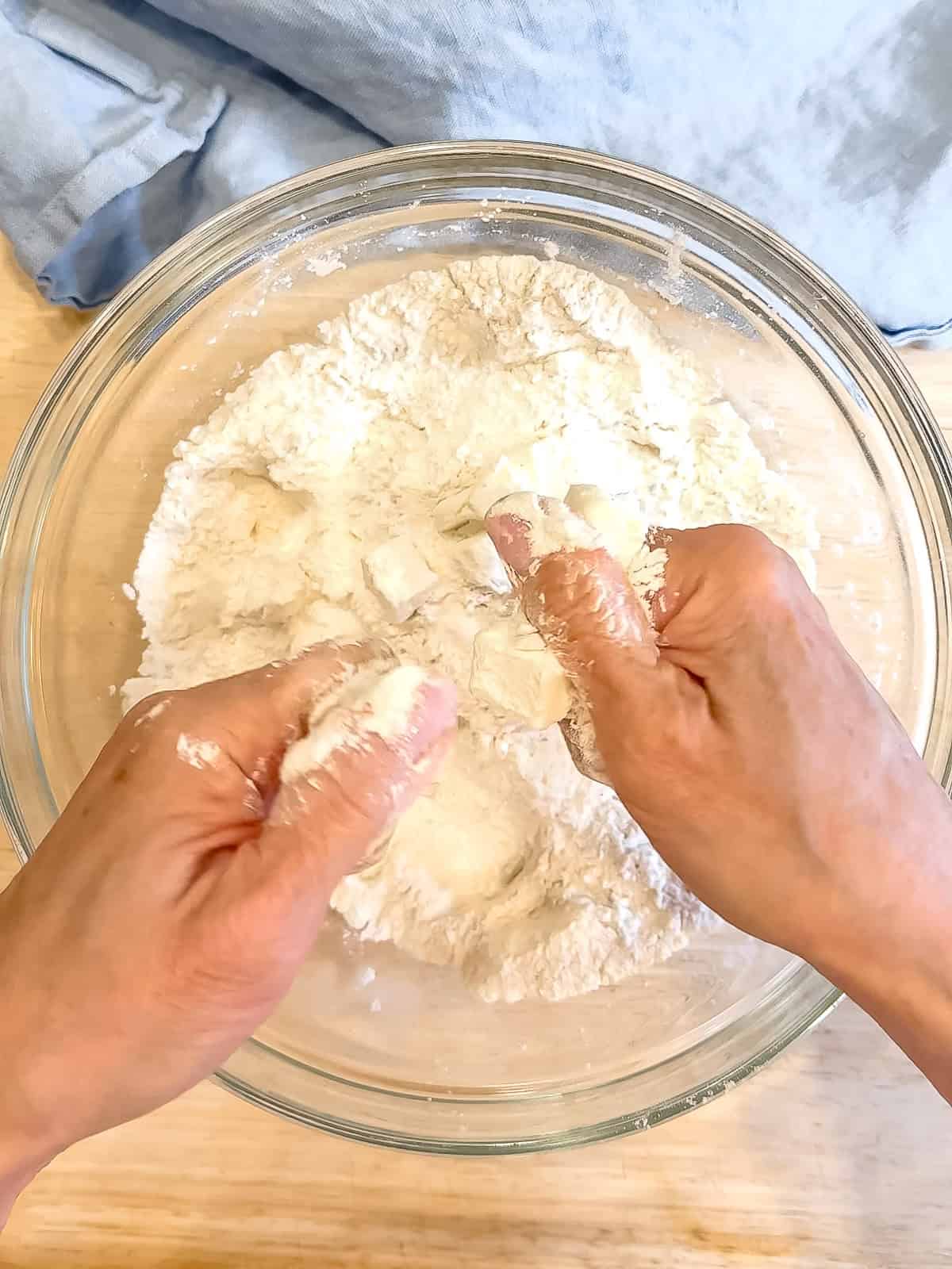 Using fingers to cut butter into all purpose flour.