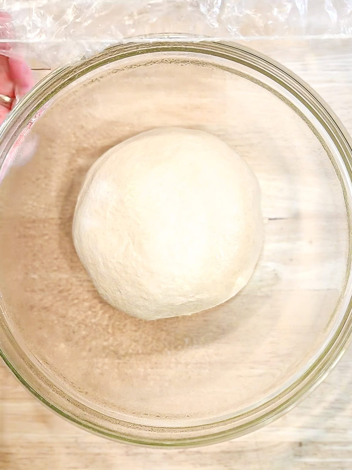 Ball of dough in a glass bowl before rising