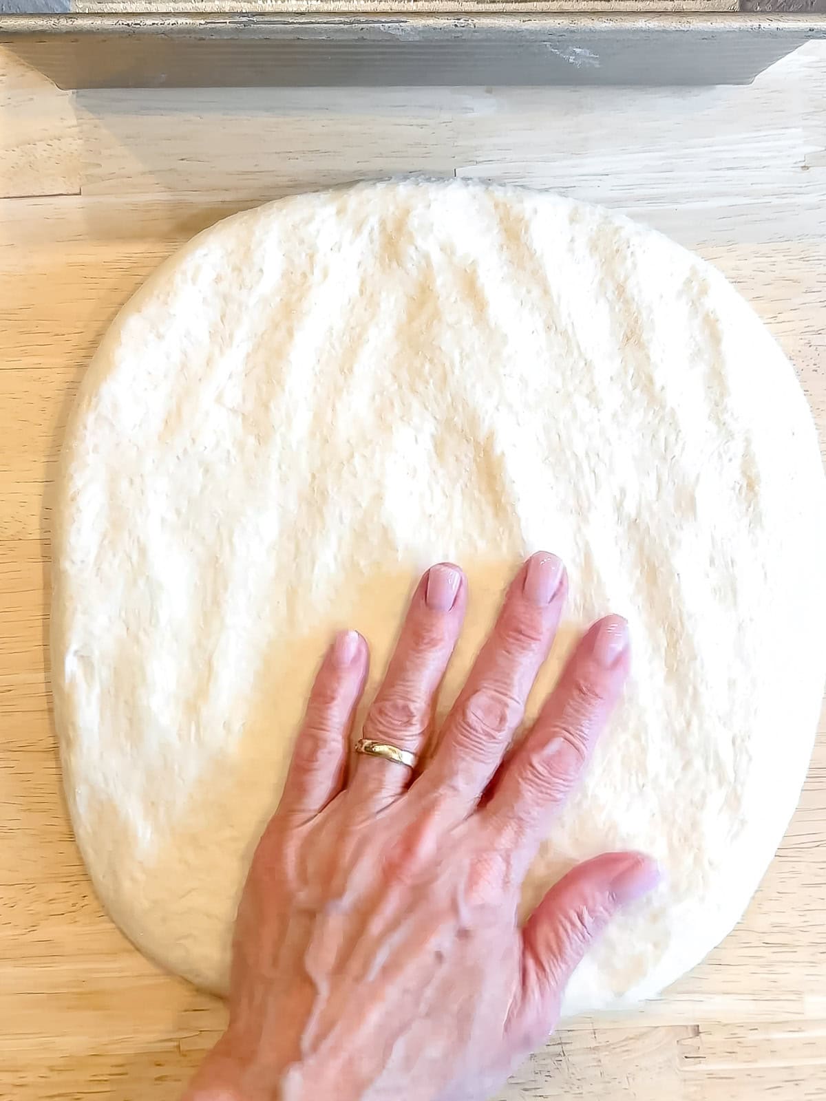 Shaping a loaf of bread on a wooden counter.