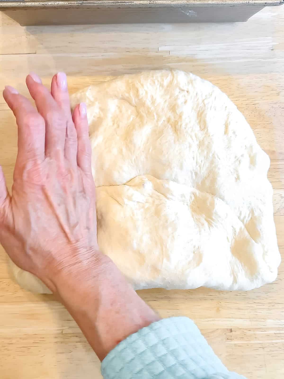 Shaping a loaf of bread on a wooden counter.