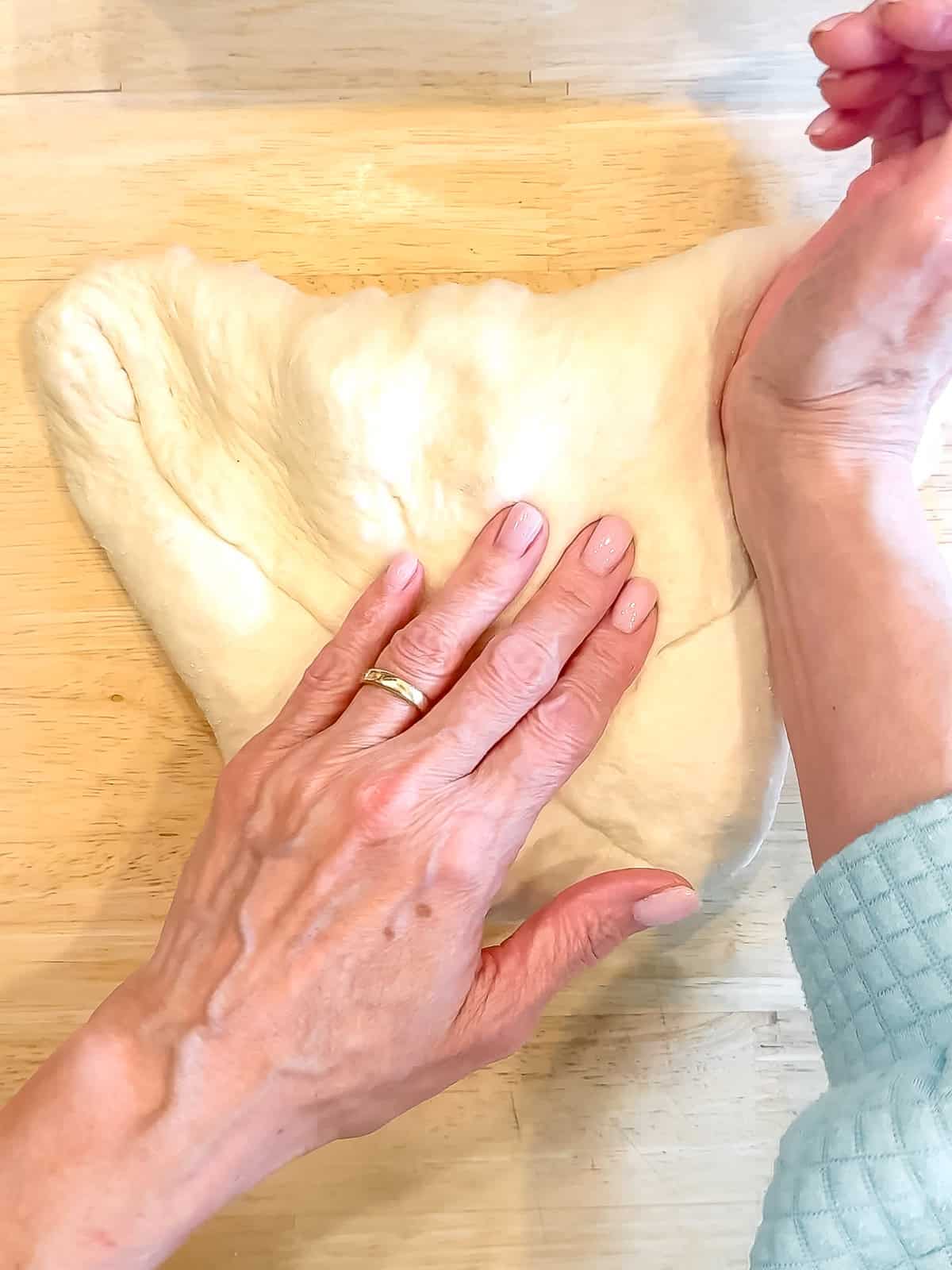 Shaping a loaf of bread on a wooden counter.