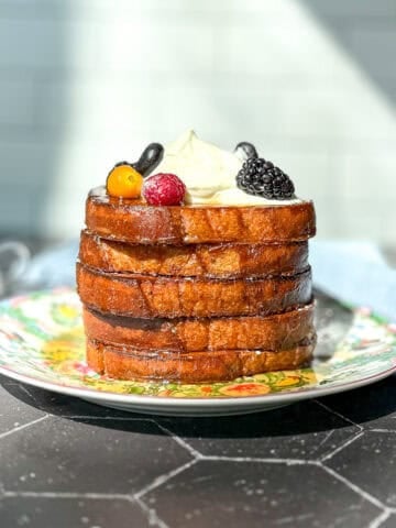 A stack of sheet pan French toast topped with Greek yogurt cream and fresh fruit.