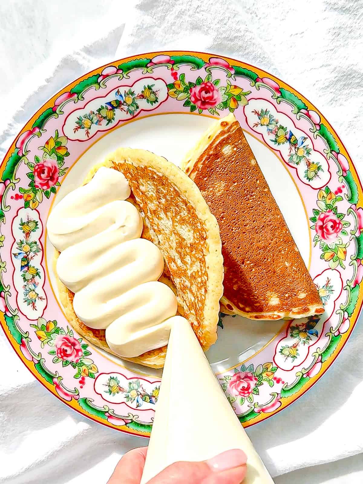 Piping cheesecake filling onto a folded pancake.