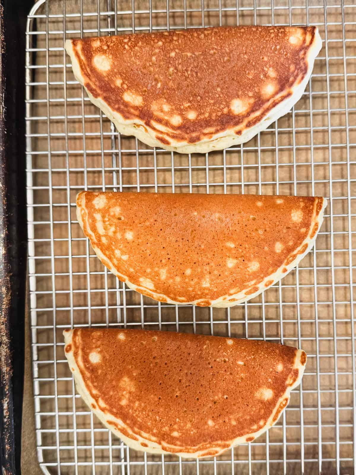 Pancakes folded like tacos on a wire rack.