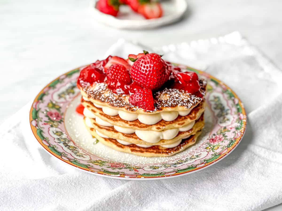 Pancakes stacked with cream cheese filling and topped with strawberry sauce and fresh strawberries.