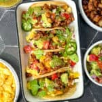 Chorizo and potato tacos in a white ceramic dish.