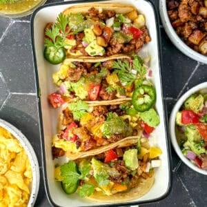 Chorizo and potato tacos in a white ceramic dish.