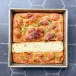 Focaccia in a square pan on a black background.