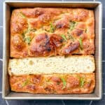 Focaccia in a square pan on a black background.