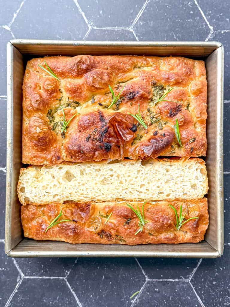 Focaccia in a square pan on a black background.