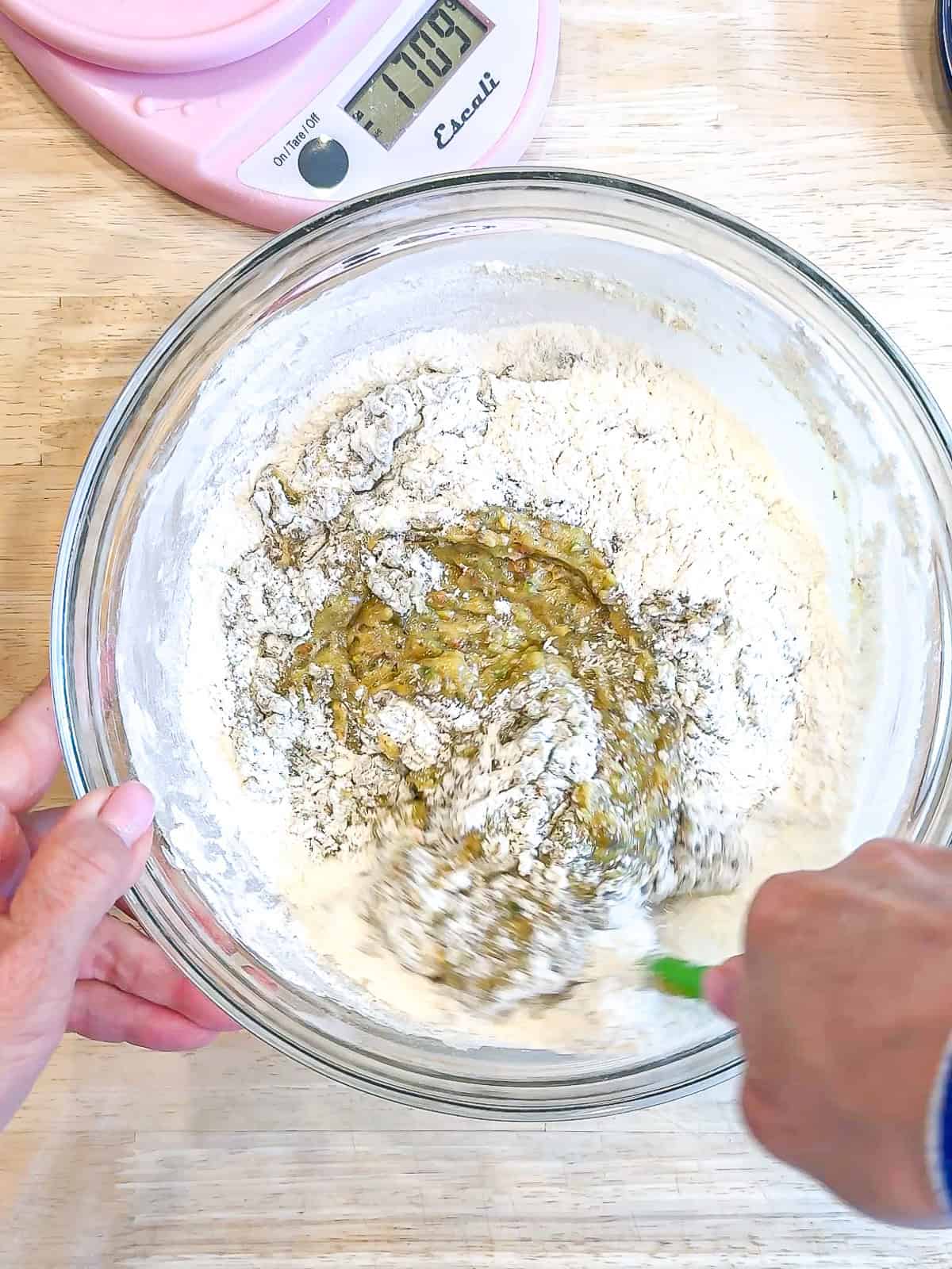 Mixing pistachio muffin batter in a glass bowl.