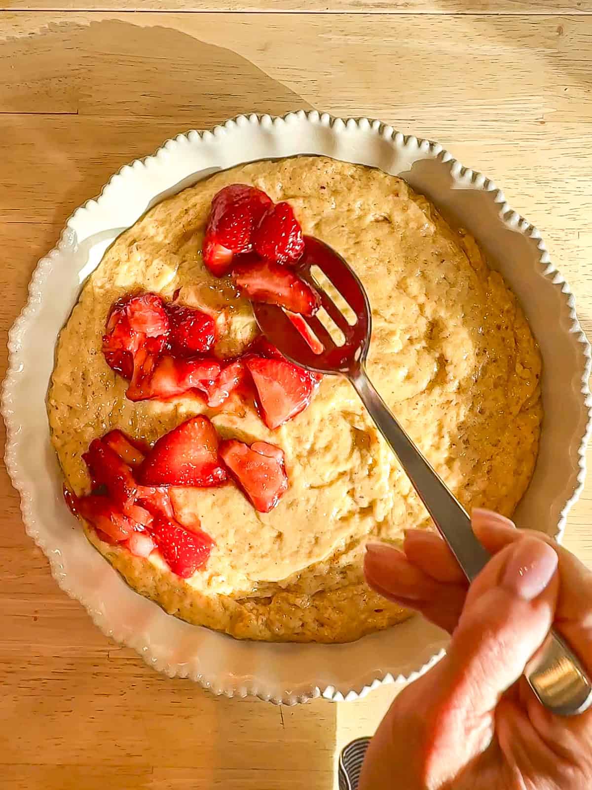 Placing strawberries on top of cake batter in a White dish
