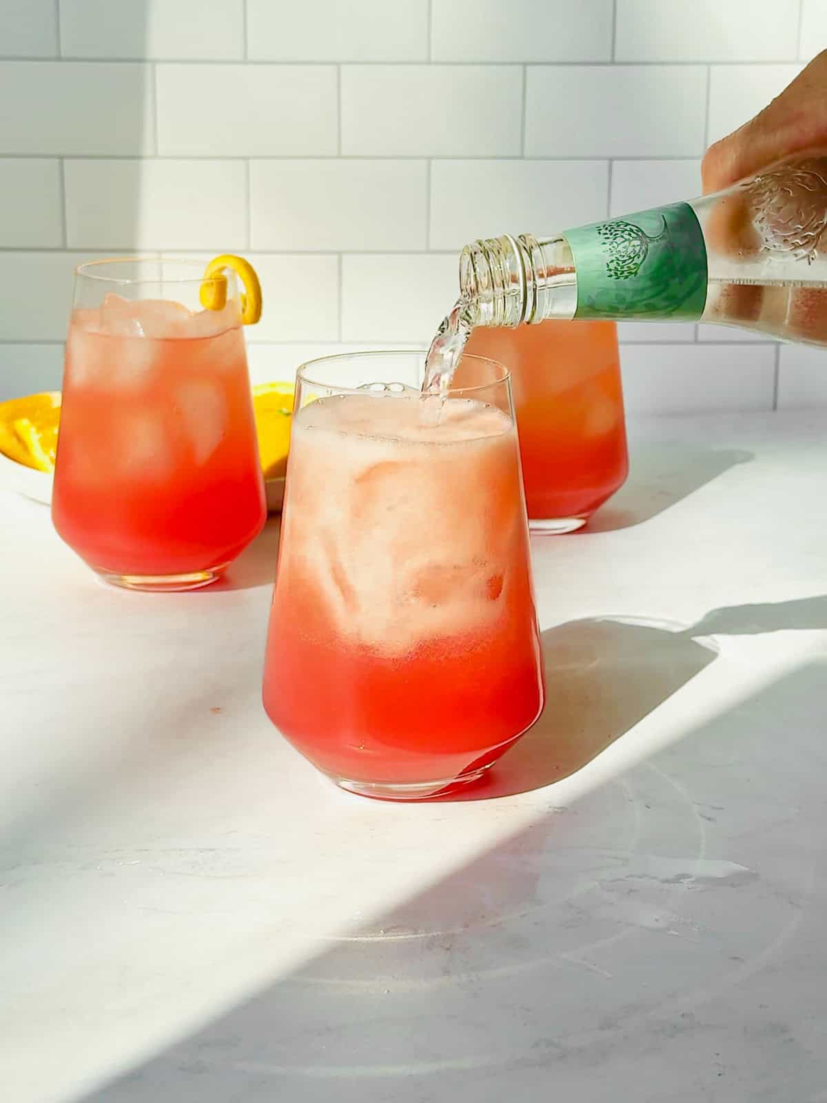A person pours a drink into a glass.