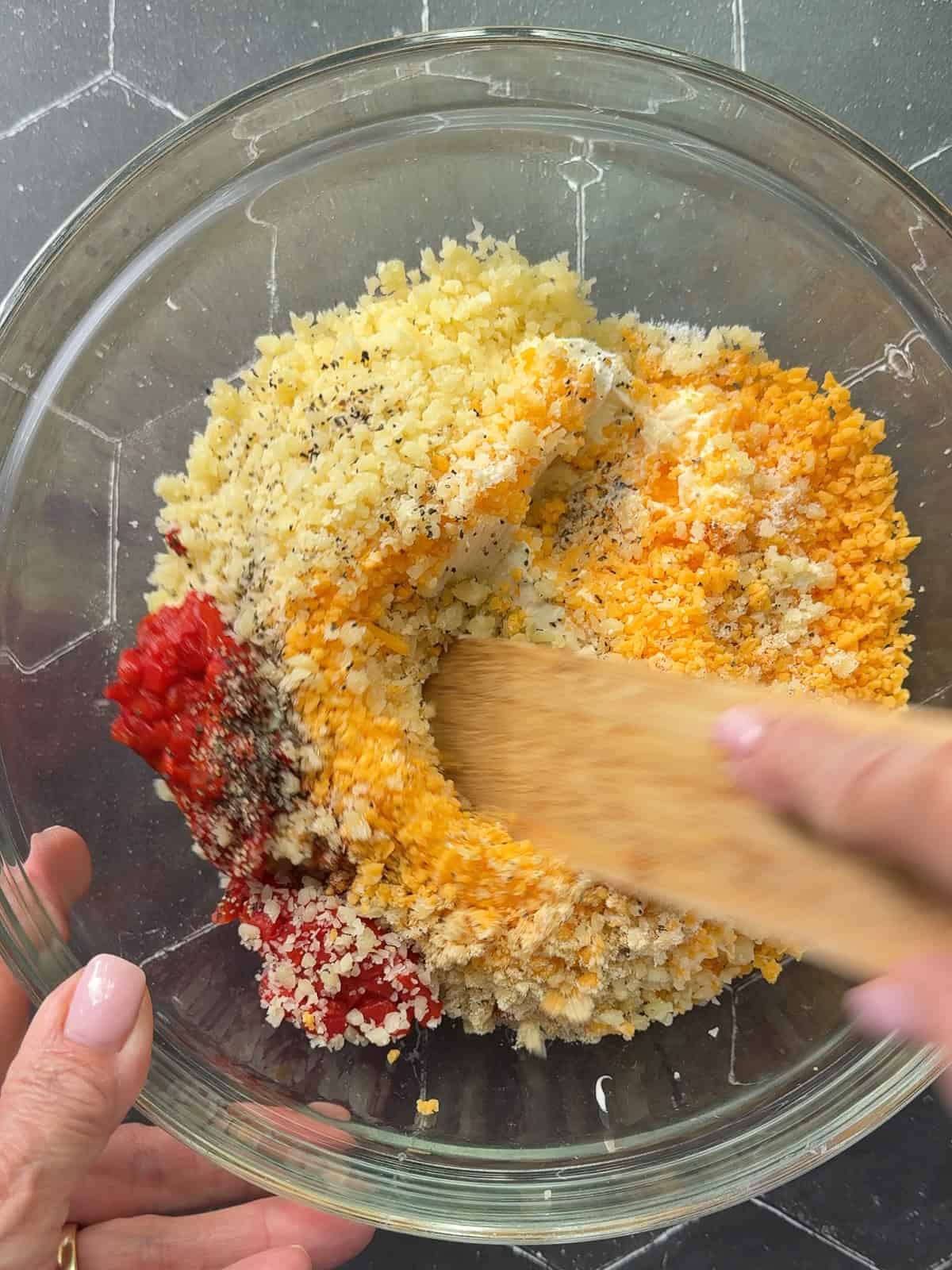 Mixing pimento cheese ingredients in a glass bowl.