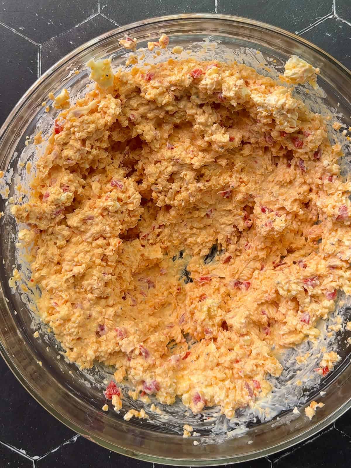 Mixed pimento cheese in a glass bowl.