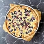 A baked blueberry topped French yogurt cake on a black background.