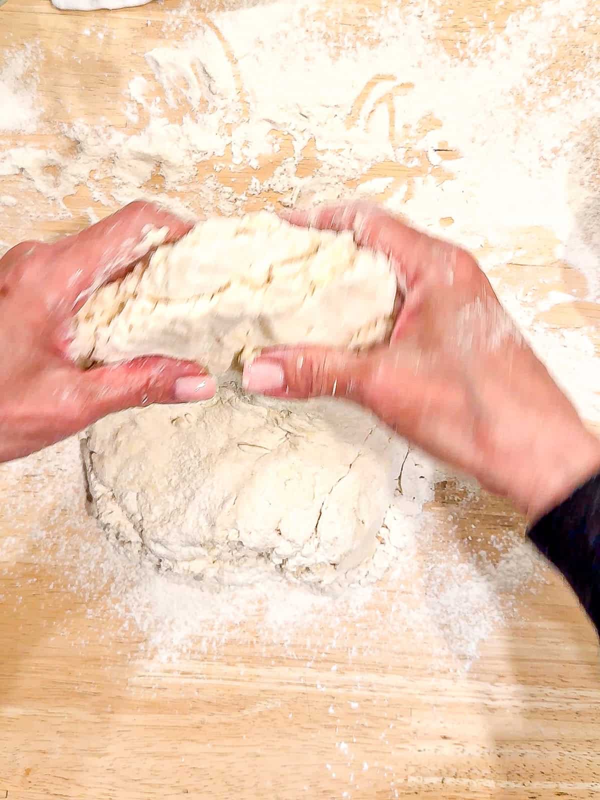 Folding biscuit dough on a floured surface.
