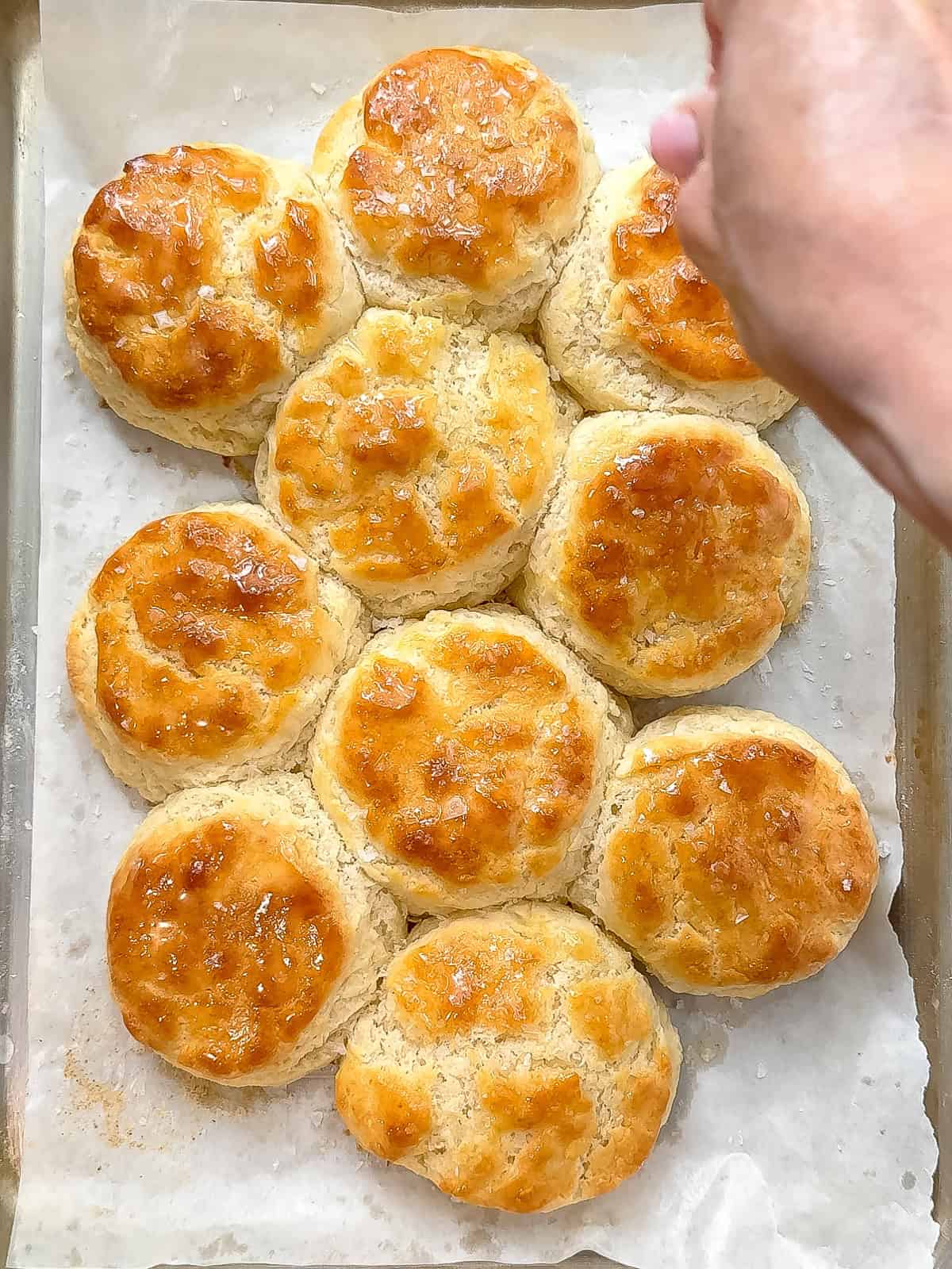 Sprinkling flaky sea salt on baked three ingredient buttermilk biscuits.