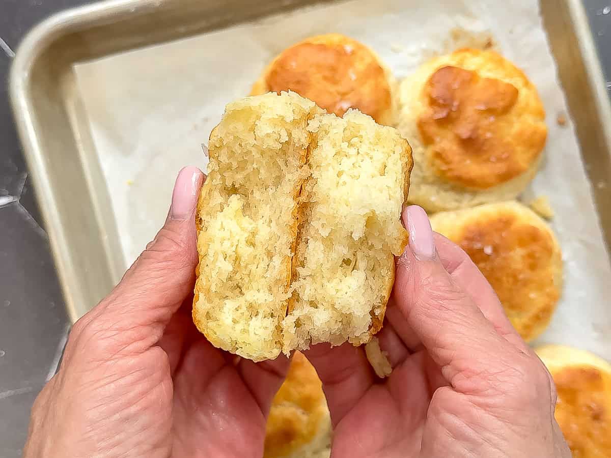 Hands holding an open three ingredient buttermilk biscuit.