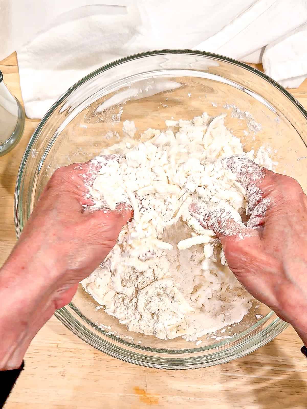 Using fingers to rub cold butter into flour in a glass bowl.