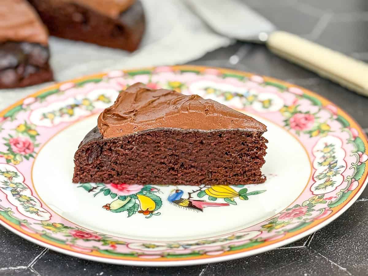A slice of chocolate cake with double chocolate buttercream on a flowered plate.