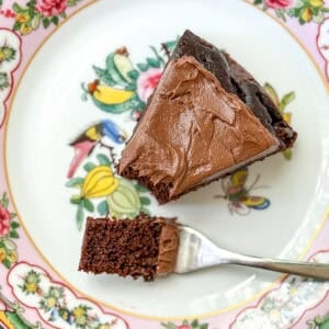 A slice of chocolate cake with double chocolate buttercream on a flowered plate.