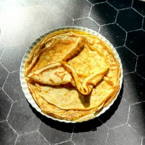The stack of crêpes on a cream colored plate.