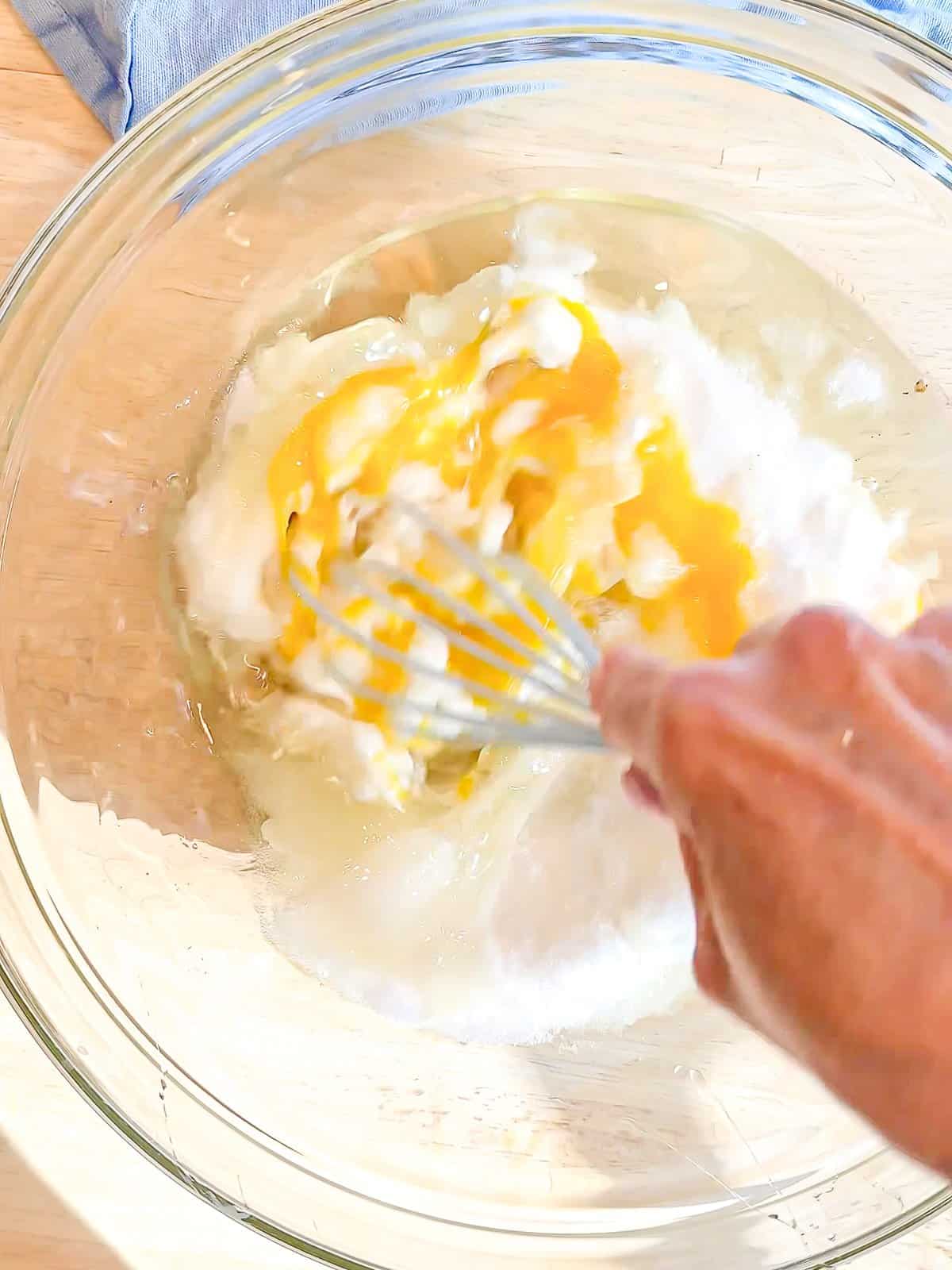 Whisking sugar into wet ingredients.