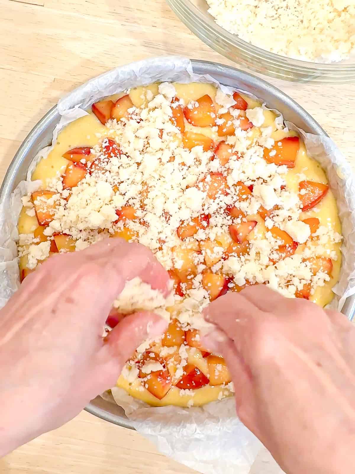 Crumbling streusel on top of a fruit covered cake.