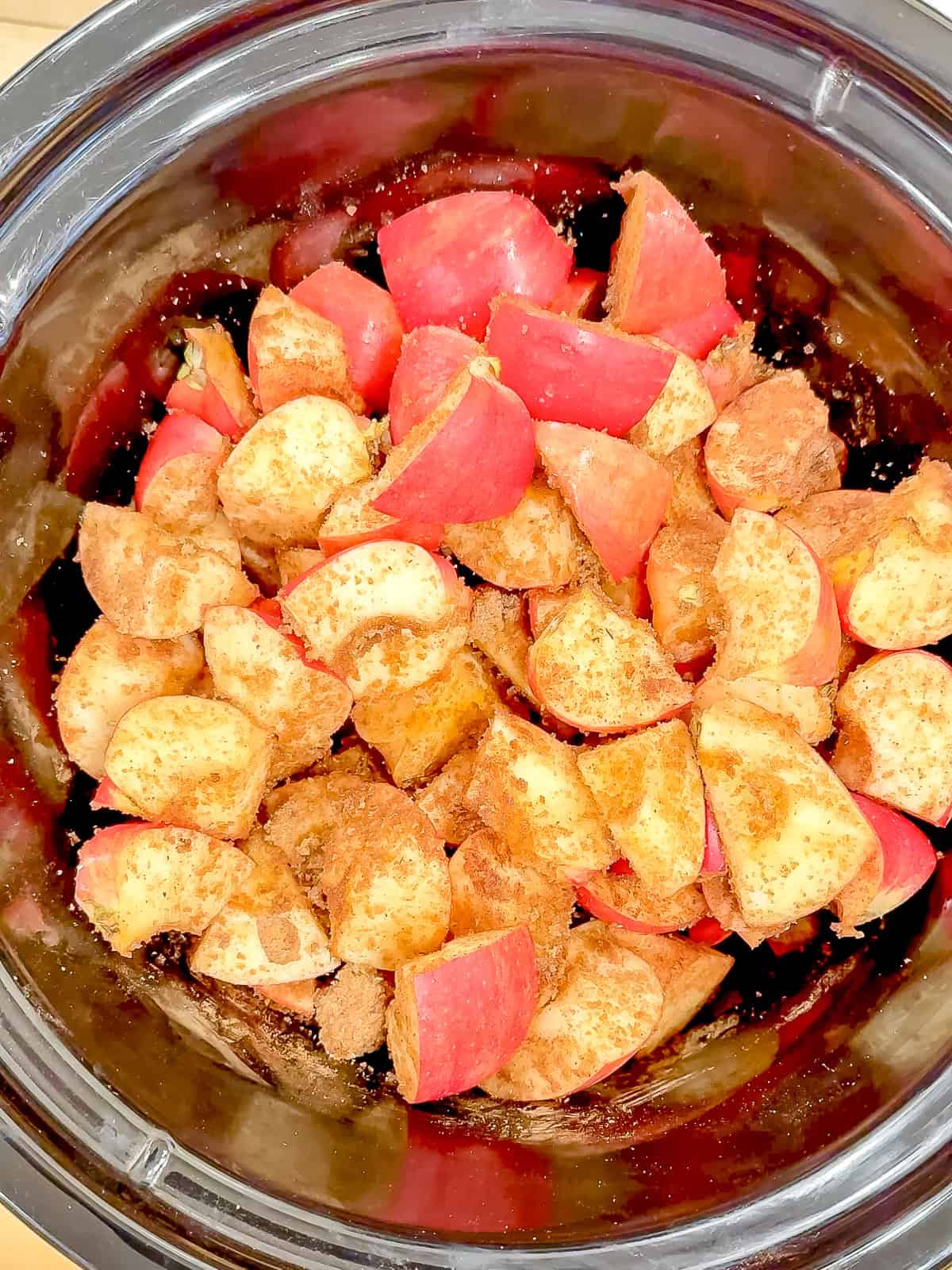 Sugar and spices added to diced apples in a slow cooker.