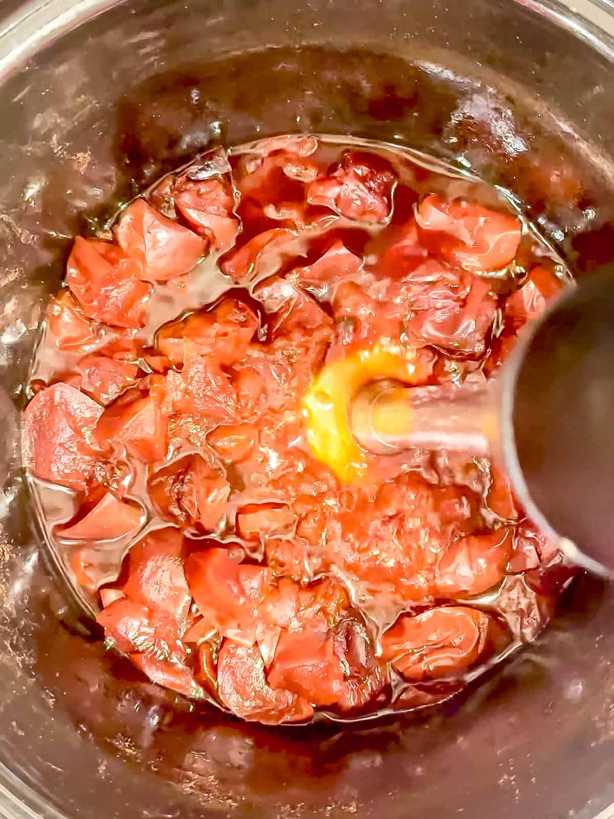 Puréeing cooked apples with an immersion blender.