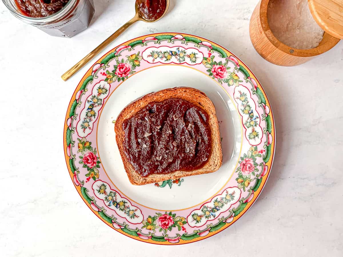 Apple butter on honey wheat bread on a floral plate.