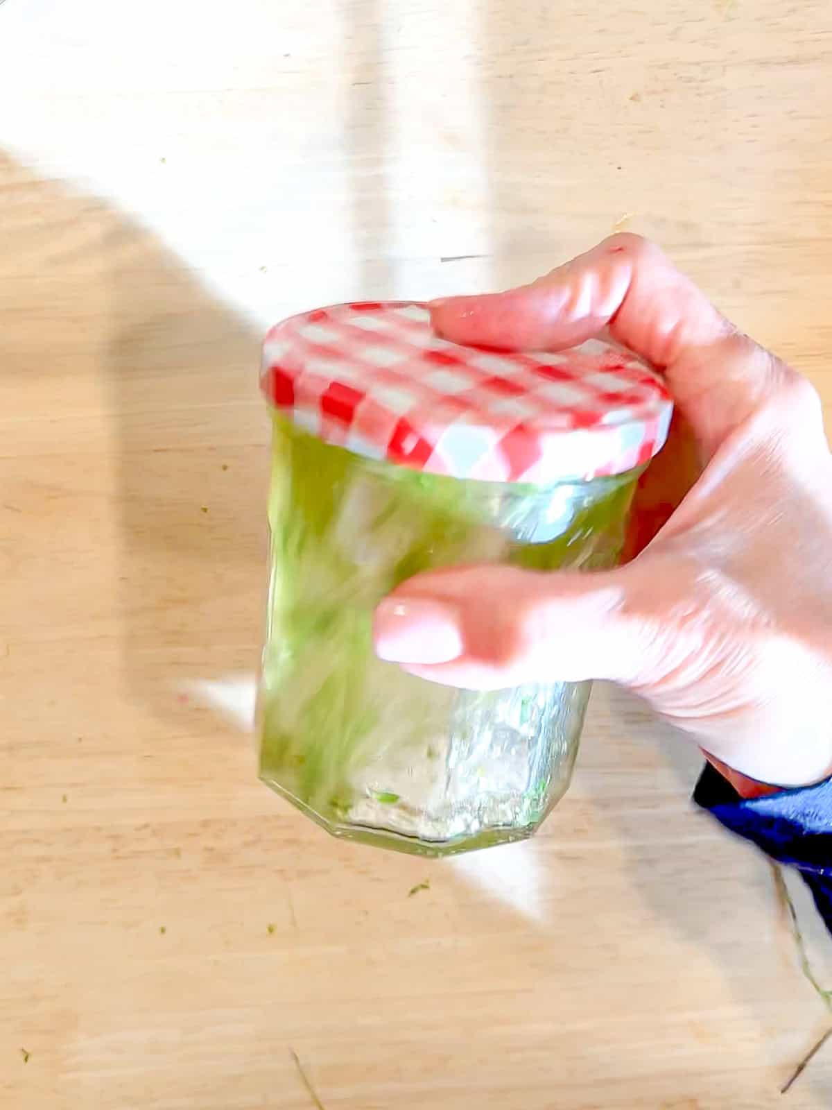 Shaking honey lime dressing in a glass jar.