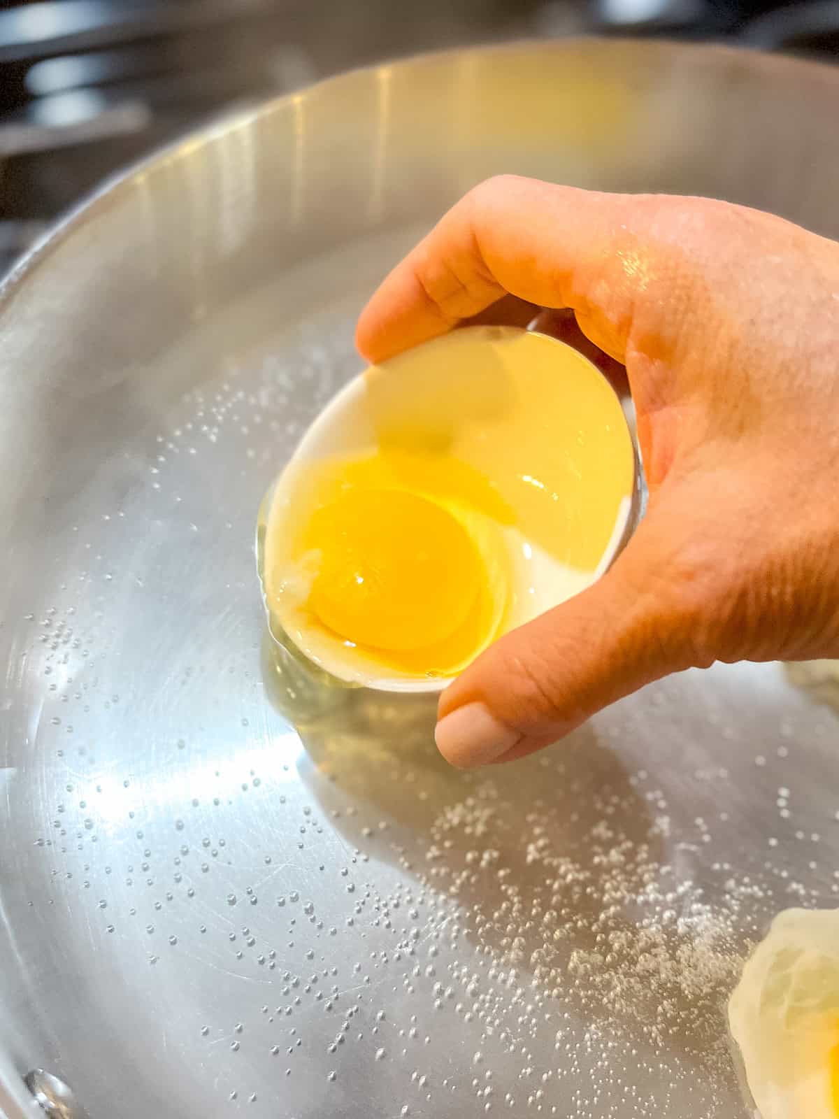 Tipping raw eggs into hot water to make poached eggs.