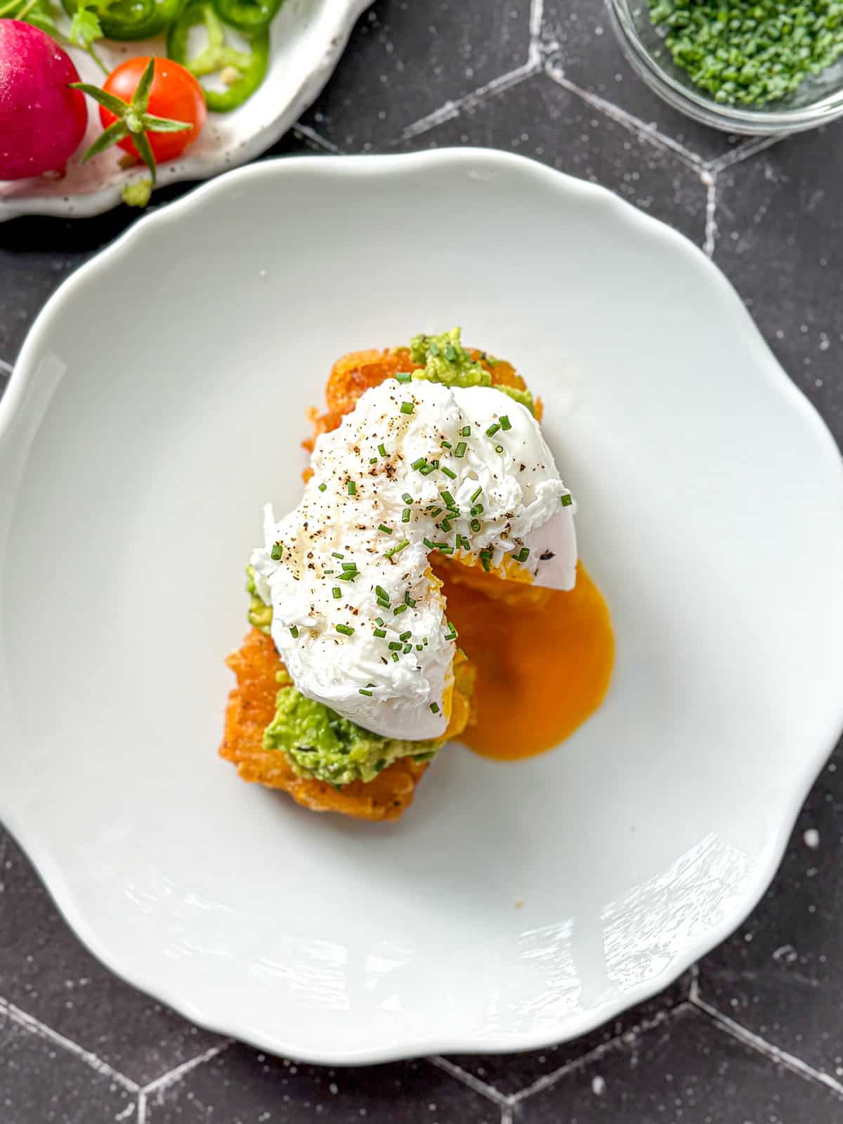 Top of a hash brown avocado toast with a poached egg.