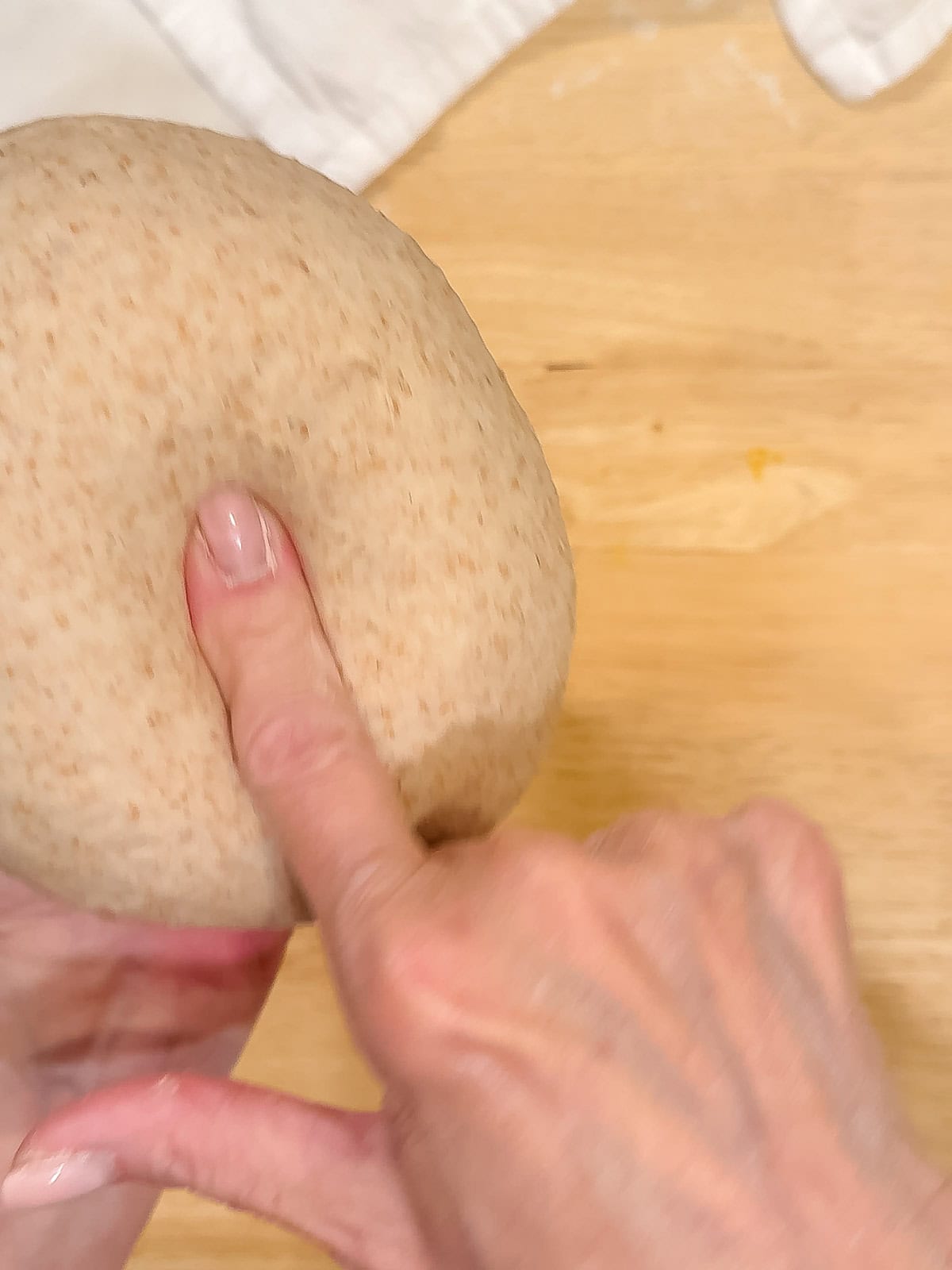 Poking a ball of dough with a finger to show that it is well kneaded.