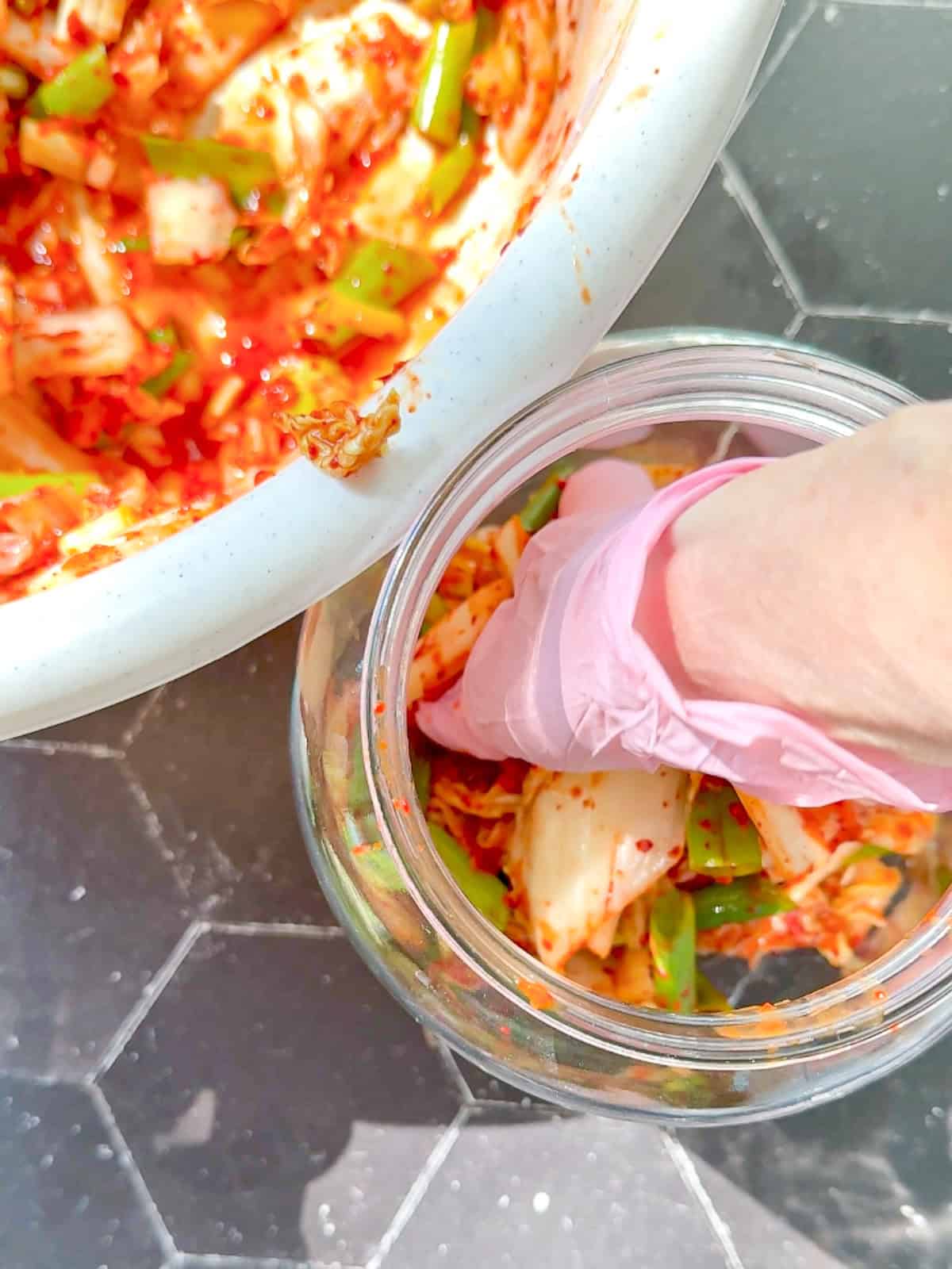 Placing kimchi into a large jar.