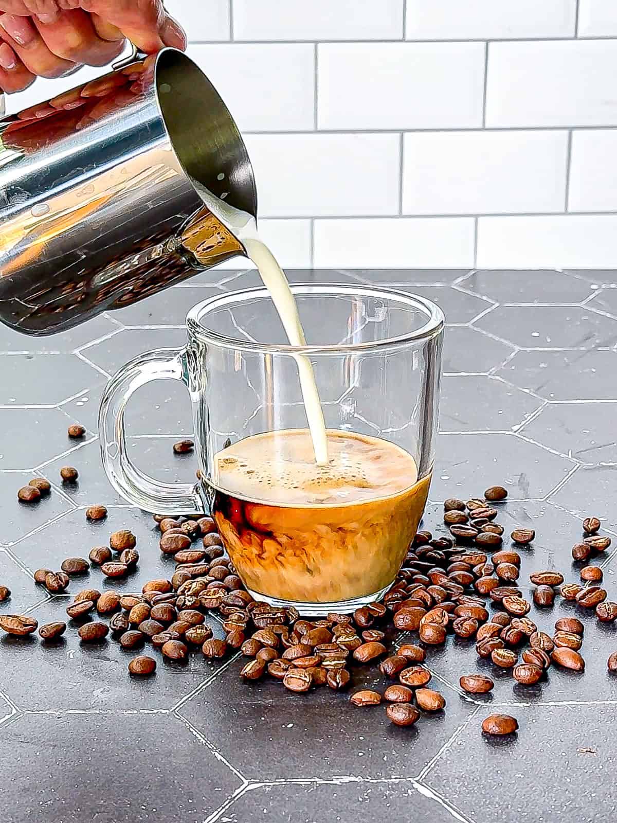 Adding steamed milk to espresso flavored with vanilla syrup.