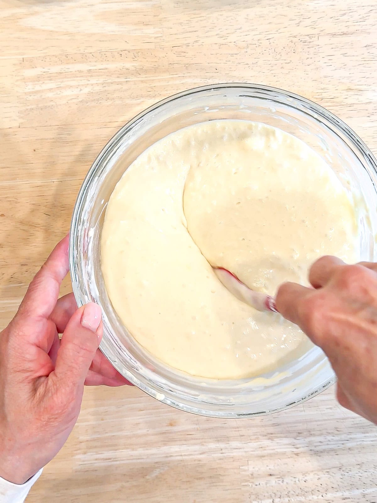 Mixing waffle batter in a glass bowl.