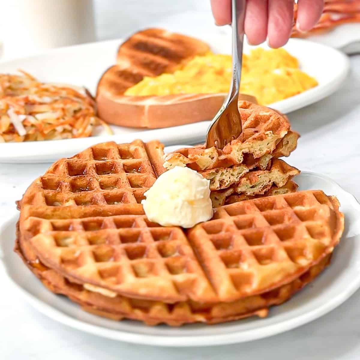 Waffle house waffle waffles on a white plate with more breakfast in the background.