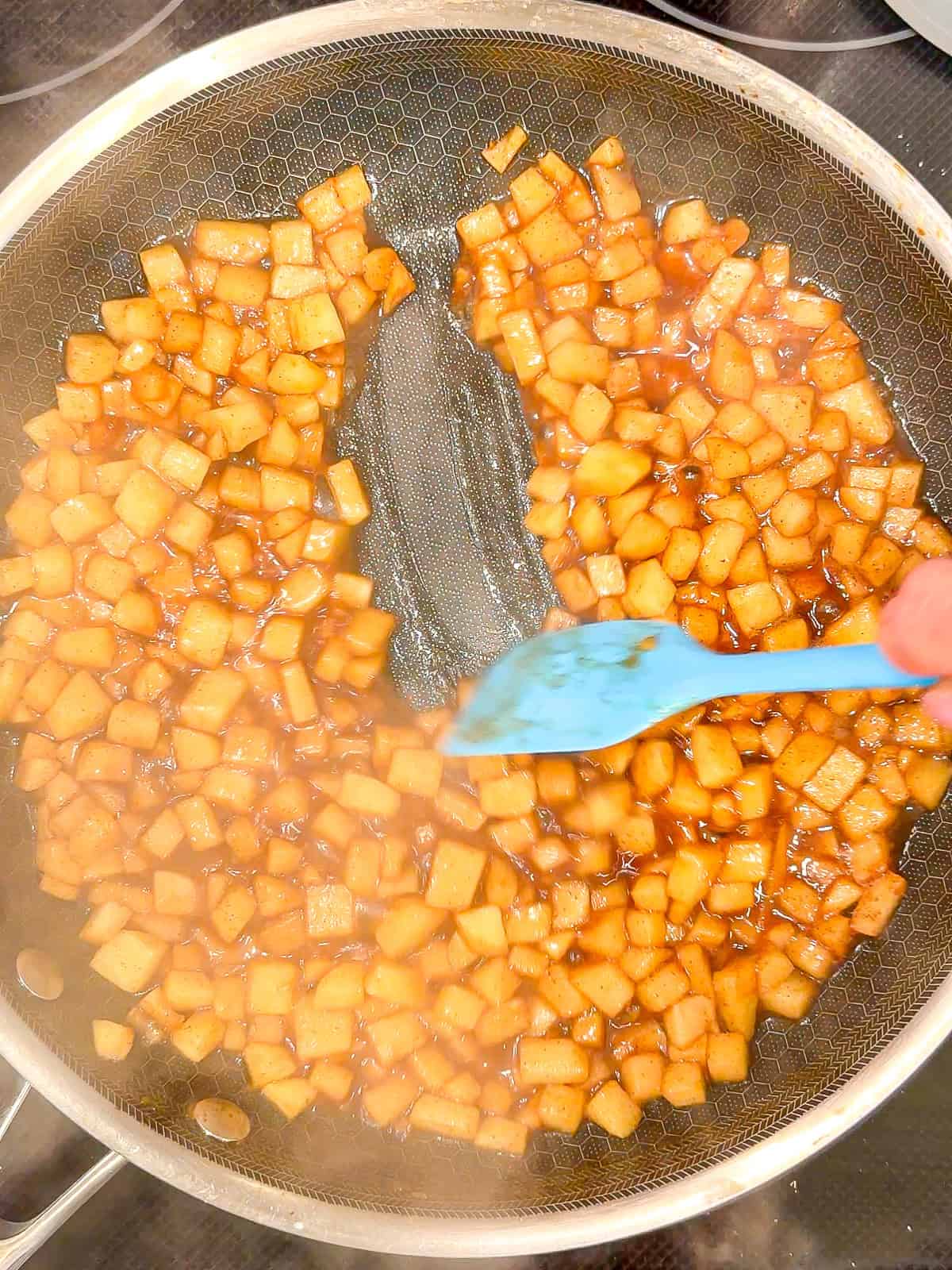 Cooked apple pie filling in a black pan.