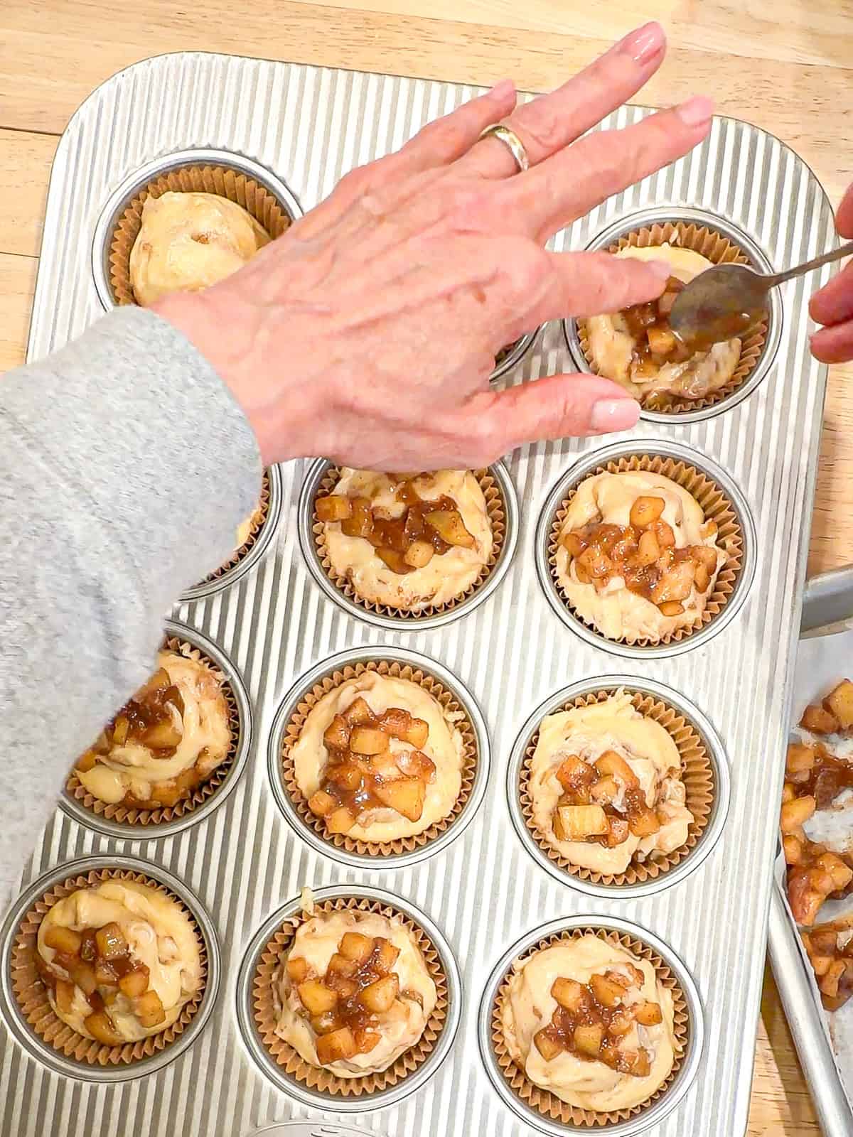 Topping apple pie muffins with more apples.