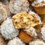 A pile of apple pie muffins, one broken in half to show the interior.