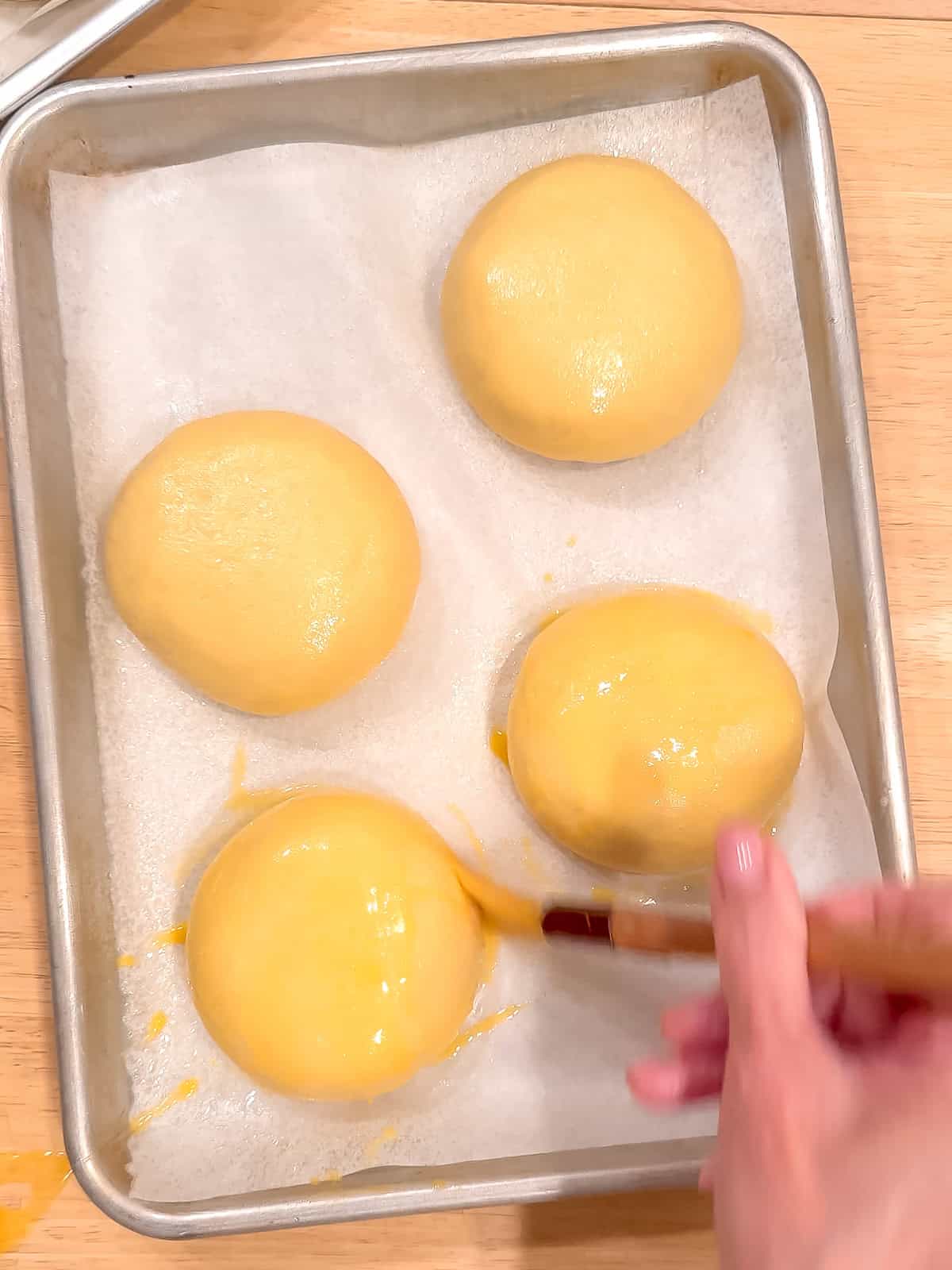 Brushing brioche dough with an egg wash before baking.