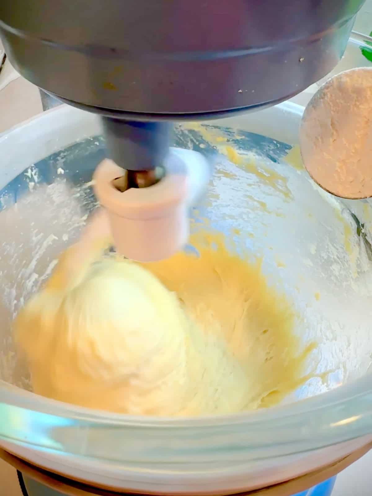 Adding 1 tablespoon of flour to brioche dough in a stand mixer.
