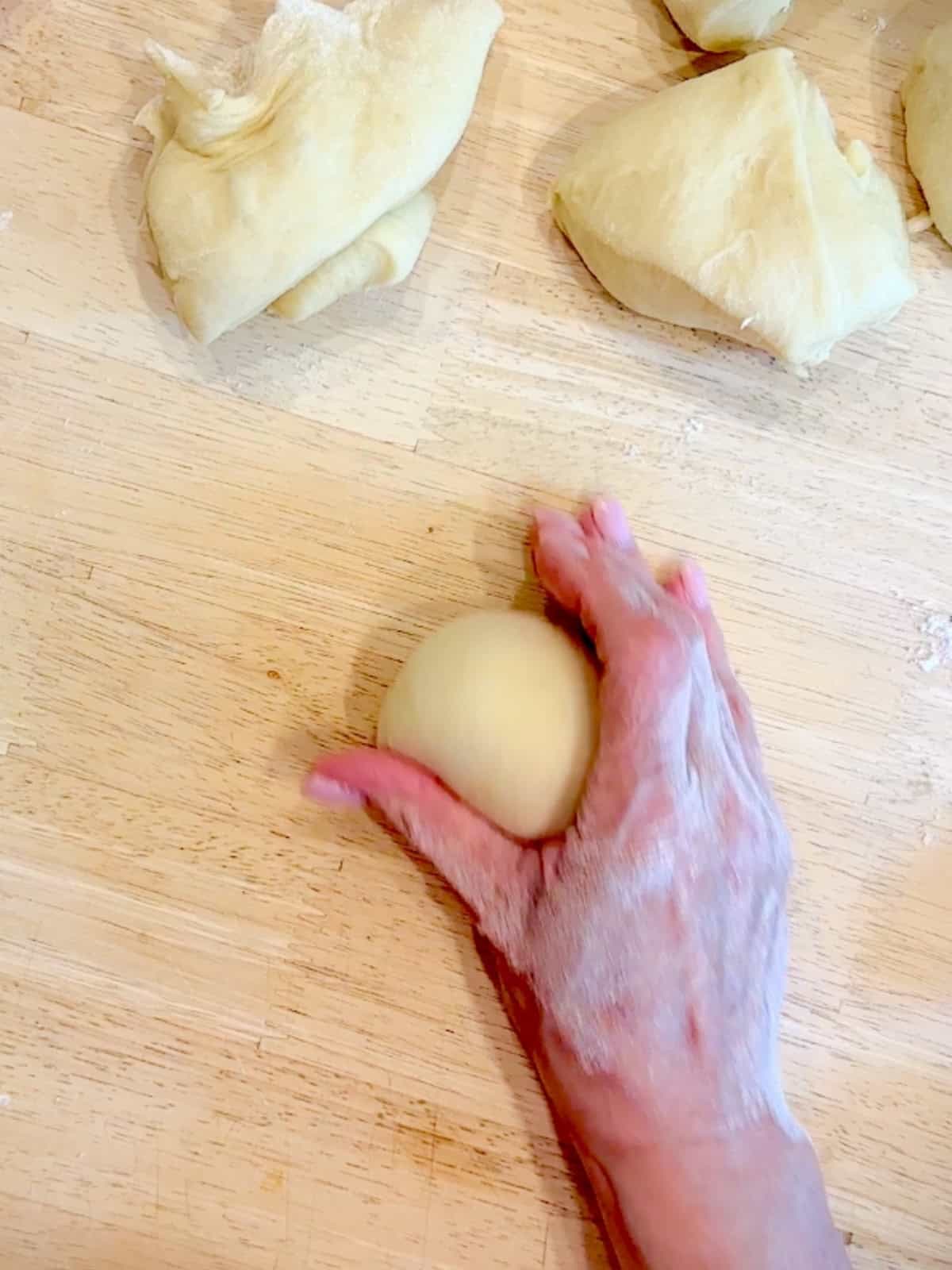 Rolling brioche dough on the counter to form a tight ball.